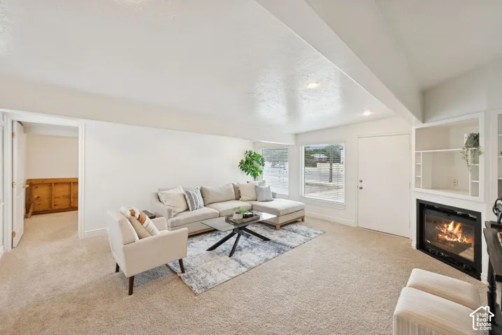 Recessed lighting, built-in shelving, carpet flooring, a window with blinds, and an integrated fireplace