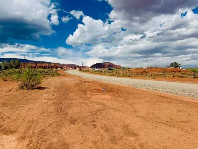 Expansive undeveloped land featuring a gravel road, natural desert landscaping, and distant rock formations