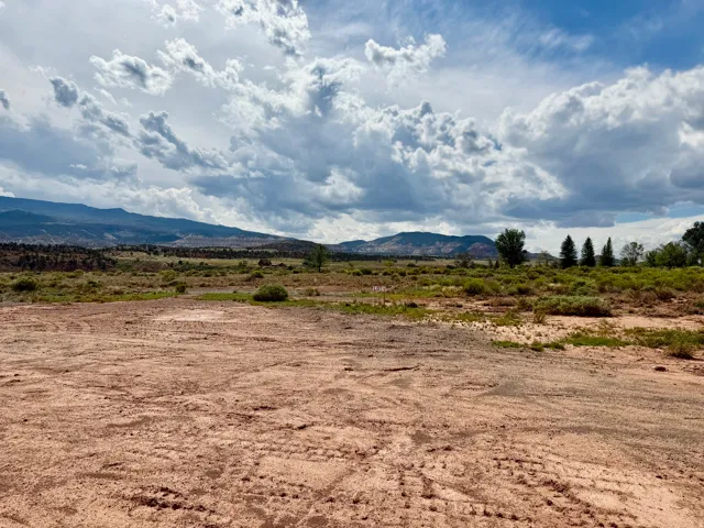 Expansive vacant lot featuring a cleared building area, natural scrub brush, and distant mountains