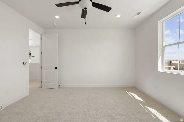 Spacious room featuring neutral carpeting, a dual-pane window, ceiling fan, and recessed lighting