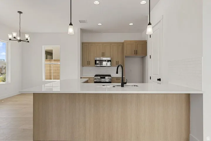 Kitchen island with a white countertop and wood-finish paneling, featuring a stainless steel sink with a matte black faucet