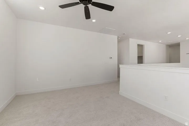 Neutral-toned carpeting throughout, recessed ceiling lighting, a dark-toned ceiling fan, and white wall finishes