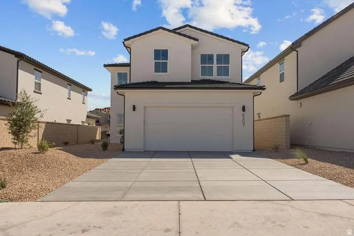 Two-story stucco exterior with a multi-pane window design, dark roof tiles, an integrated garage, and a concrete driveway