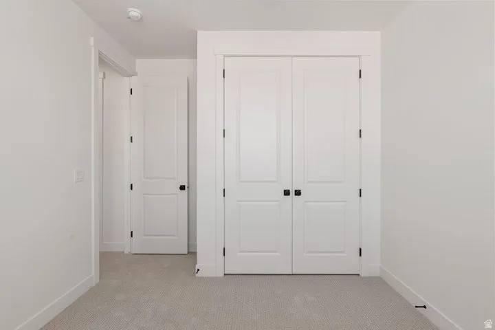 Neutral tone wall paint, carpet flooring, two-panel interior doors, matte black door hardware, and white trim