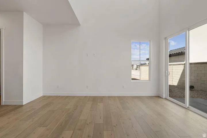 Vaulted ceilings, wood-finish flooring, white walls, and a sliding glass door