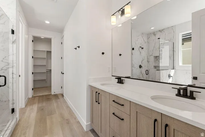 Dual vanity with light wood-finish cabinetry, white countertop, and integrated sinks