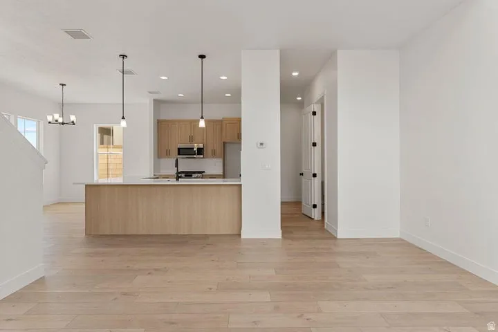Wood-finish flooring throughout, featuring a kitchen island with white countertop, recessed lighting, and modern pendant light fixtures