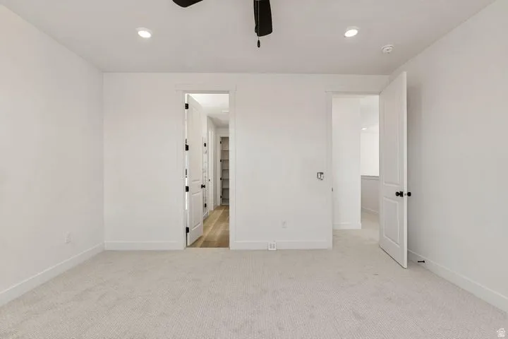 Recessed ceiling lighting, white walls, and light-toned carpet