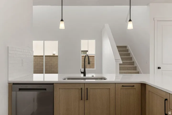 Contemporary kitchen island with a stainless steel sink, matte black faucet, integrated dishwasher, and wood-finish cabinetry