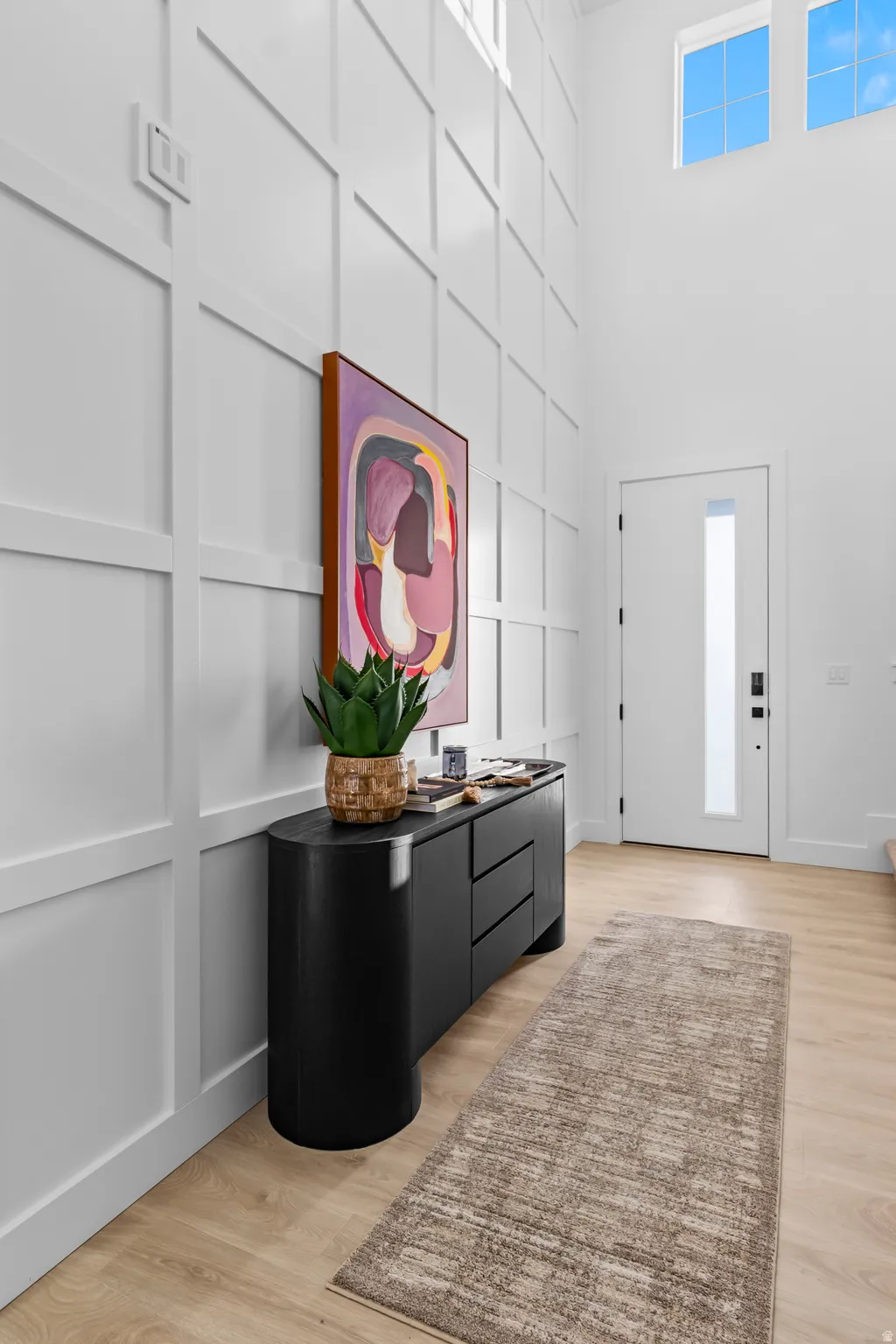 Double-height ceiling, extensive wall paneling, light wood-finish flooring, and upper-level windows