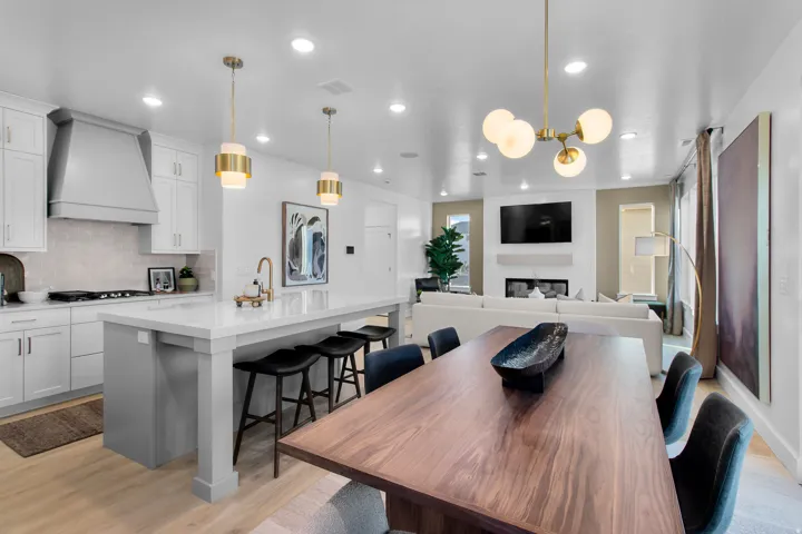 Gourmet kitchen with white cabinetry and a large center island, gas range with a custom range hood, and wood-finish flooring throughout