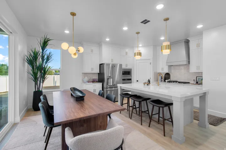Modern kitchen featuring white cabinetry, stainless steel appliances, a large center island with seating, and wood-finish flooring