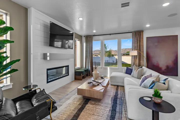 Spacious living area featuring a linear fireplace, shiplap accent wall, recessed lighting, wood-finish flooring, and expansive windows