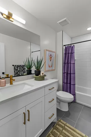 White shaker-style vanity with brass hardware, integrated rectangular sink, and light-toned countertop