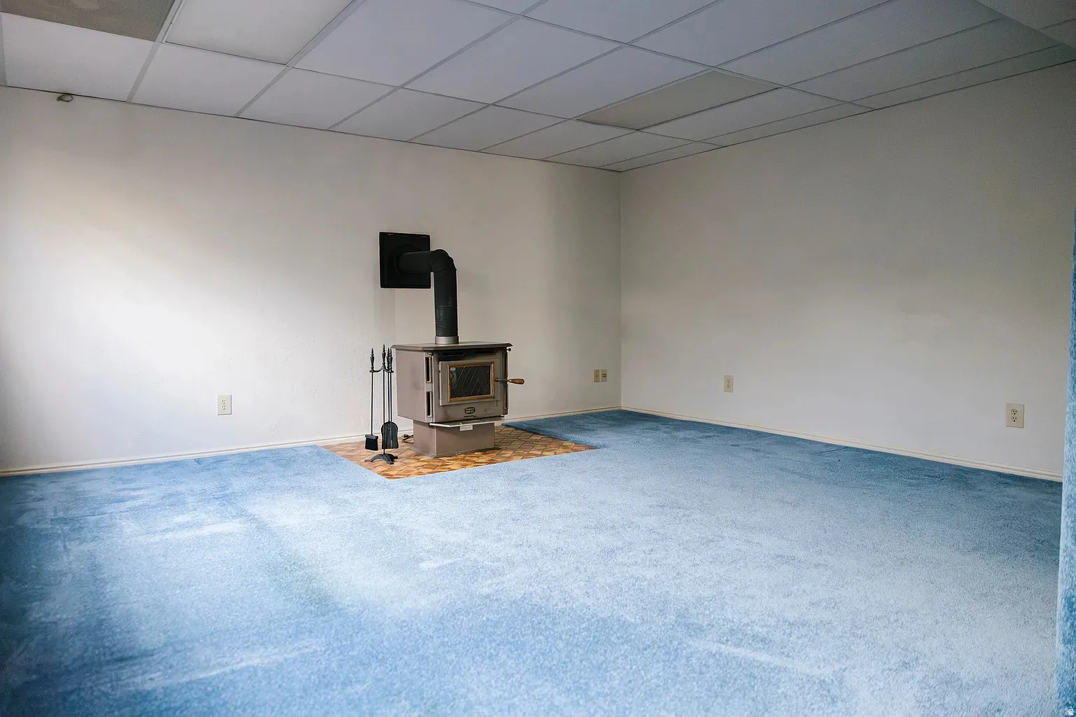 Room featuring a wood-burning stove with a metal flue, set on a tiled hearth