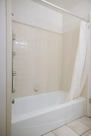 Bathtub with white tile surround and square floor tiles