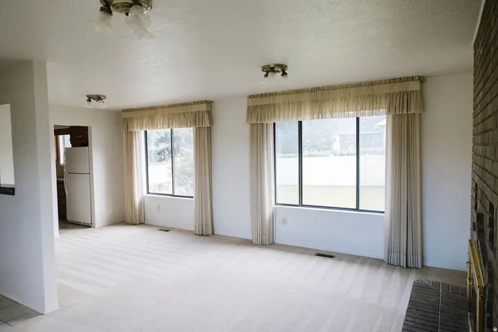 Open-concept living area with light-toned carpet flooring and neutral walls