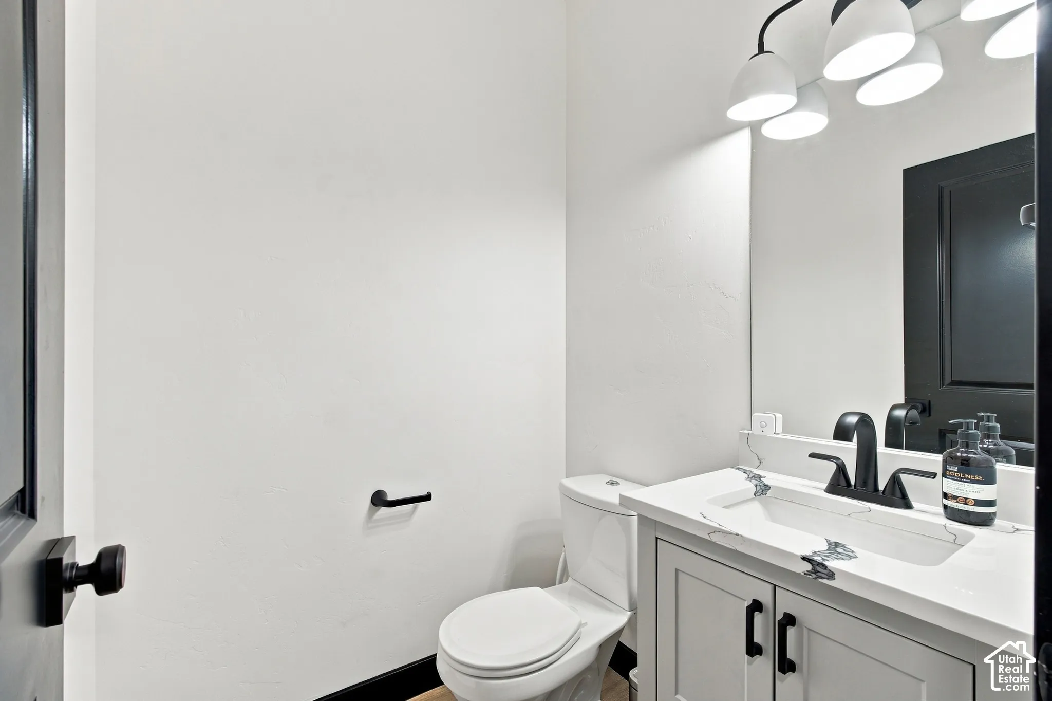 White vanity with integrated sink, black faucet, black framed mirror, and contemporary sconce lighting
