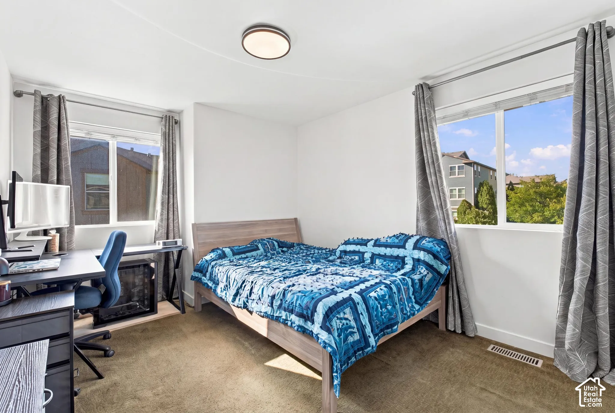 Bright room with two large windows, a flush-mount ceiling light fixture, and neutral-toned carpeting
