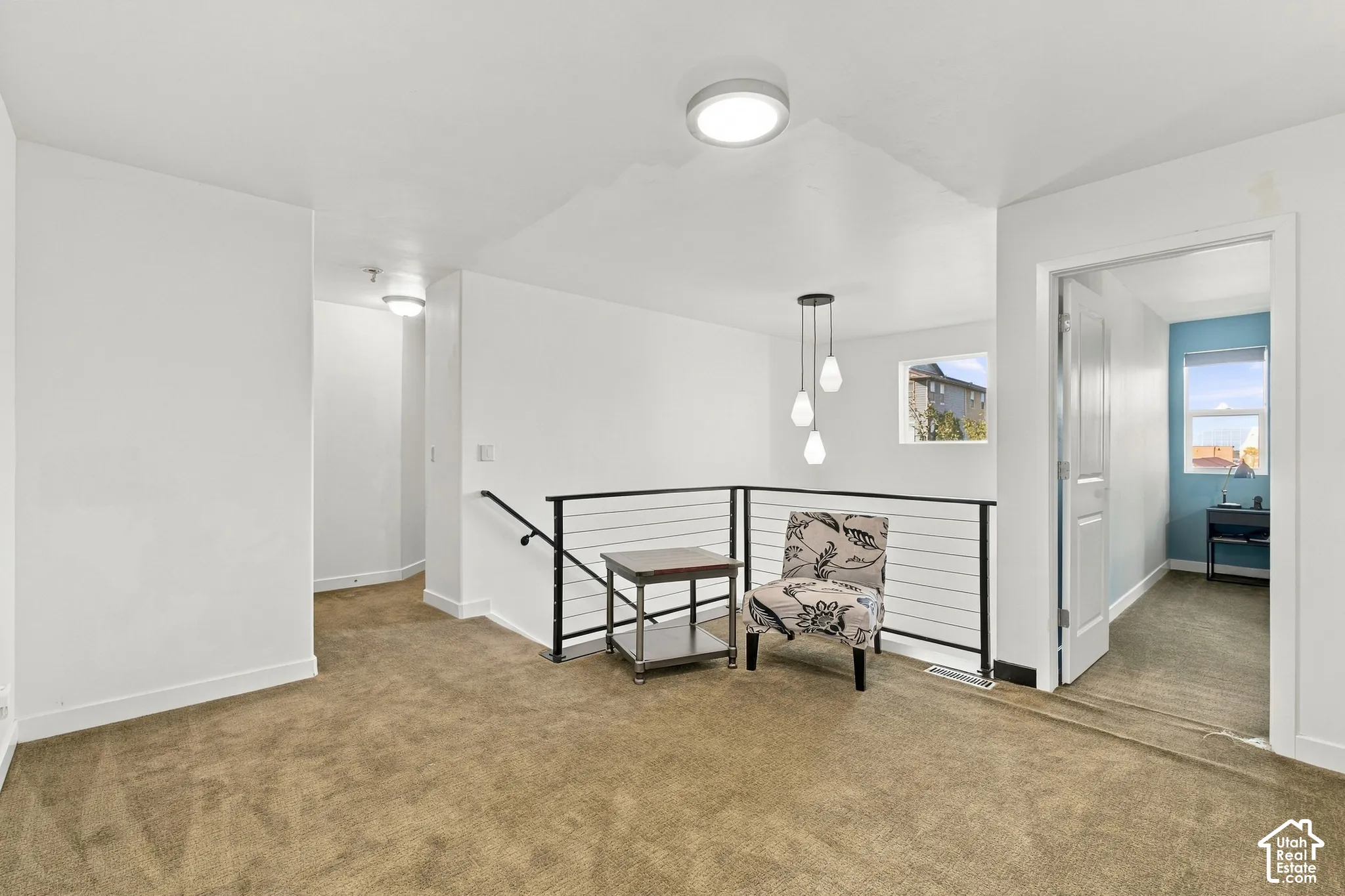 Carpeted landing with white walls, contemporary black metal railing, and recessed lighting