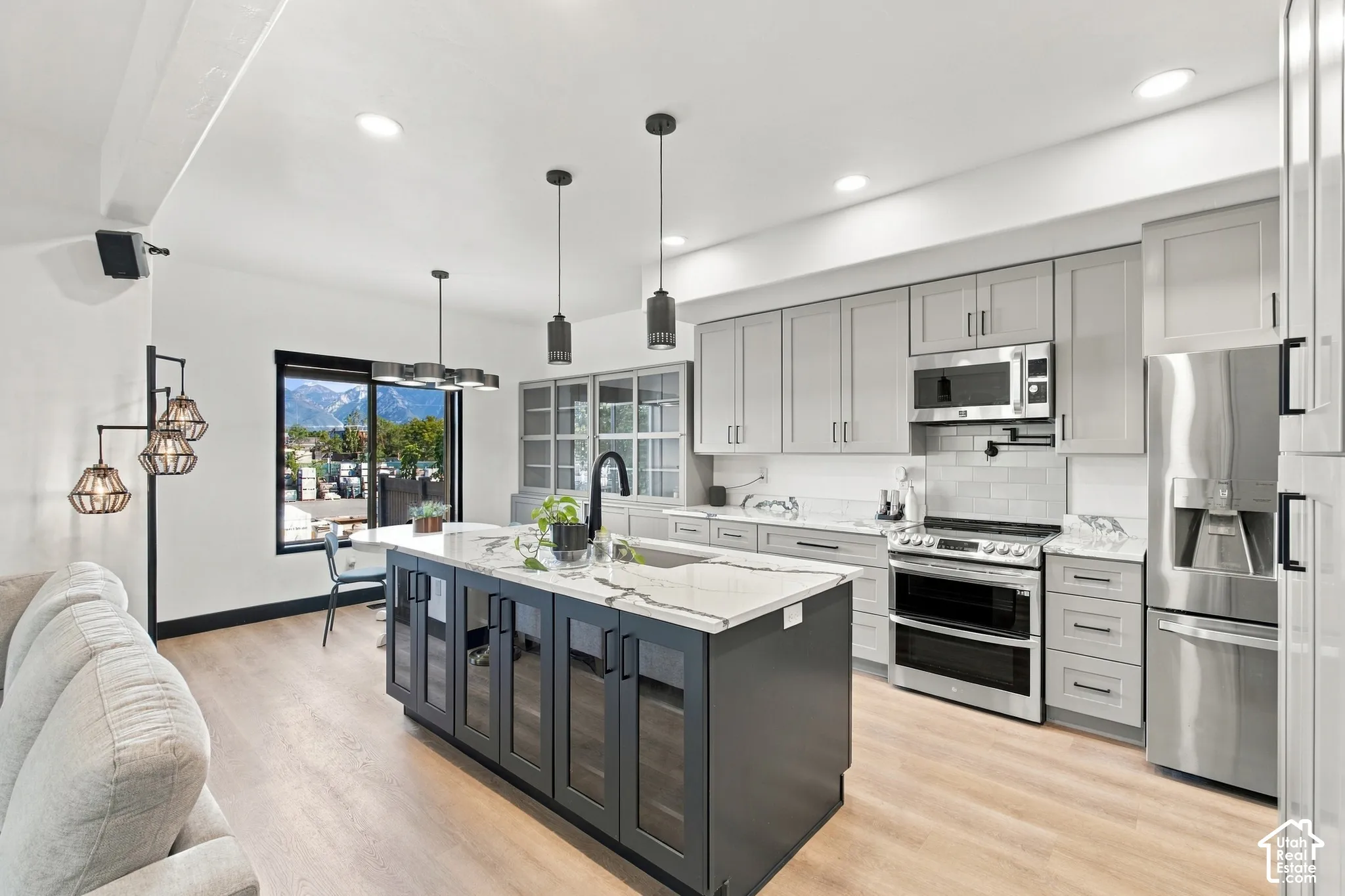 Open-concept kitchen with a large center island, light wood-finish flooring, recessed lighting, and stainless steel appliances