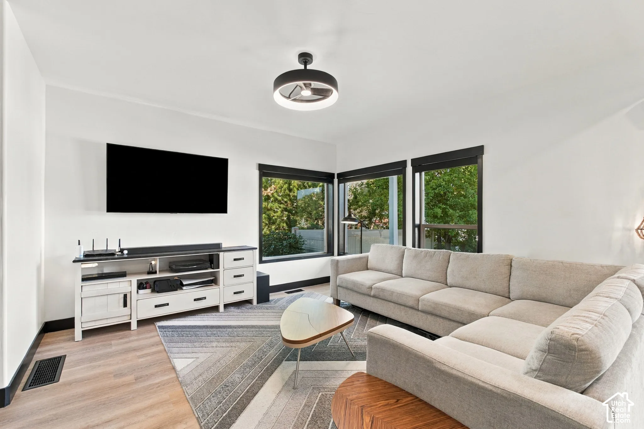 Corner window placement, wood-finish flooring, white walls, and a contemporary ceiling fixture