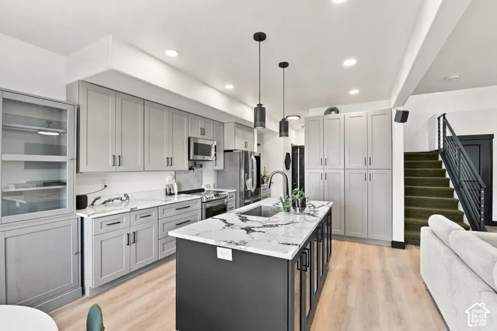 Kitchen featuring light wood-finish flooring, a central island with a sink, pendant lighting, and recessed ceiling lights
