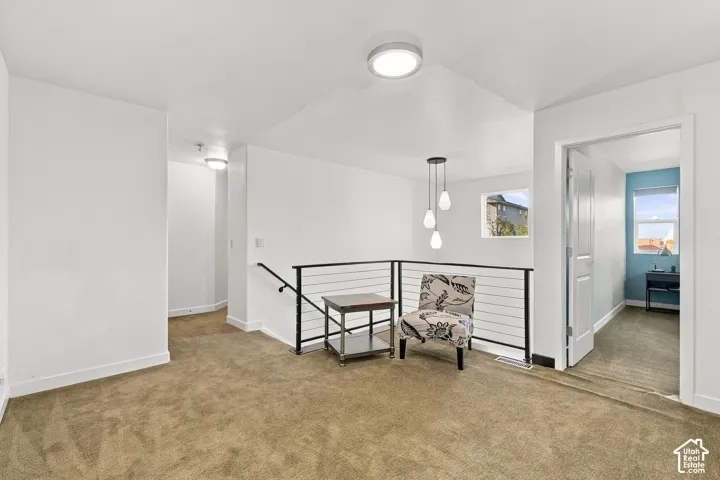 Carpeted landing with white walls, contemporary black metal railing, and recessed lighting