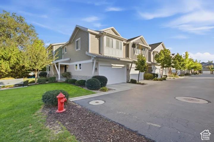 Multi-level property with light-toned siding, stone accents, and an attached garage