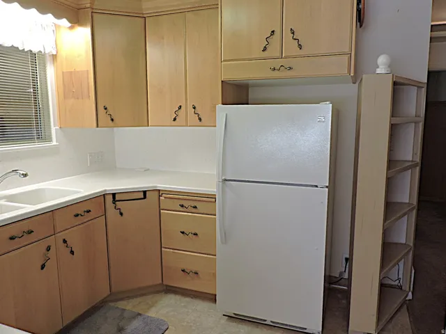 U-shaped kitchen with light wood-finish cabinetry, solid surface countertops, and a double basin sink