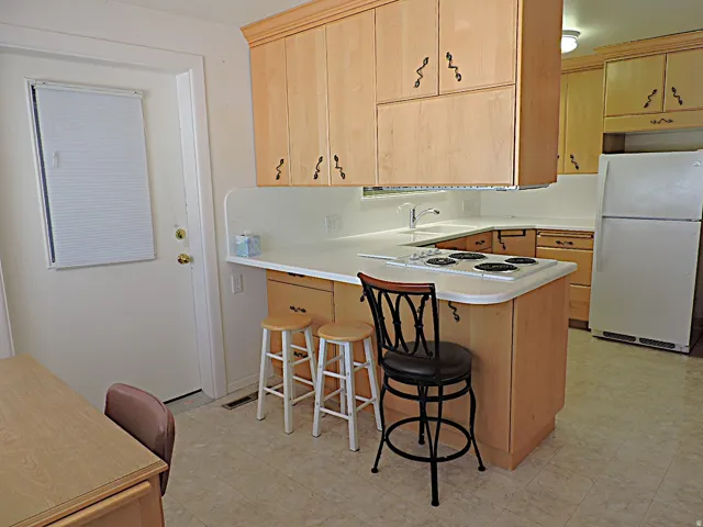 Kitchen featuring wood cabinetry, white countertops, a built-in cooktop, and a double-basin sink