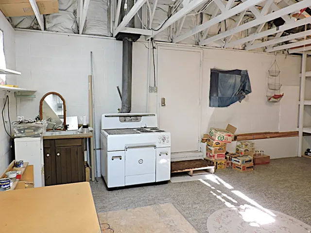 Open ceiling joist construction, white painted block walls, and existing built-in shelving