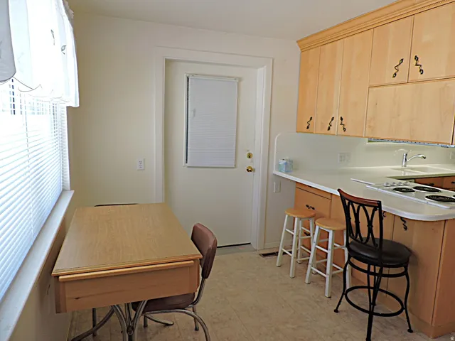 Light wood-finish cabinetry with decorative hardware, white countertops, built-in cooktop
