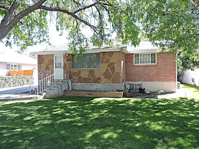 Exterior featuring stone veneer and brick siding, a front entry with metal railing, and a sizable front lawn