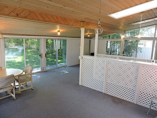 Wood-paneled ceiling with exposed beams, sliding glass doors to the exterior, recessed lighting, and a skylight