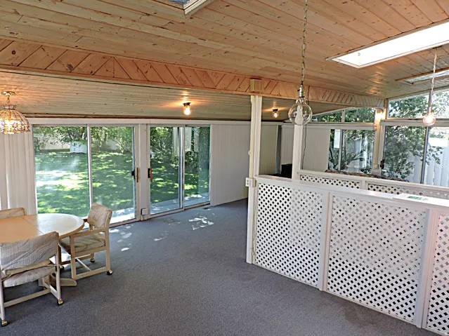 Wood-paneled ceiling with skylights, overhead lighting, and sliding glass doors opening to the exterior