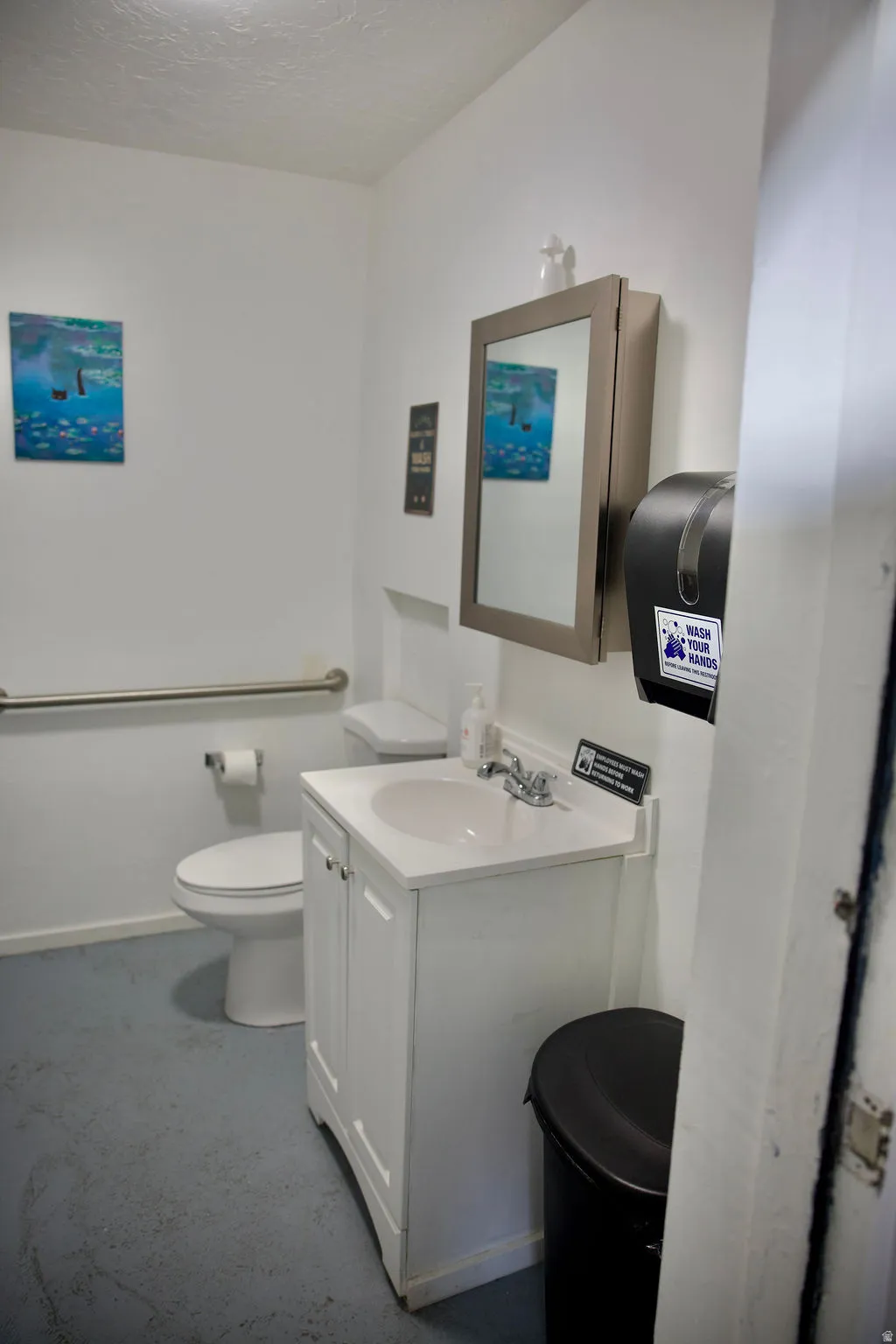 Compact bathroom featuring a white vanity with integrated sink, chrome faucet, and wall-mounted mirrored cabinet