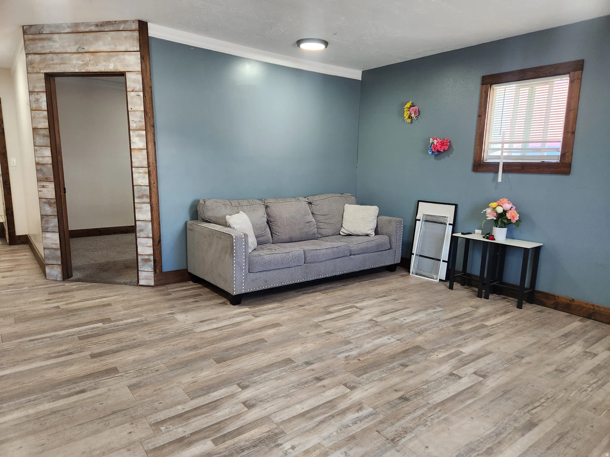 Wood-finish flooring throughout, complemented by a distressed wood-paneled doorway and a wood-framed window