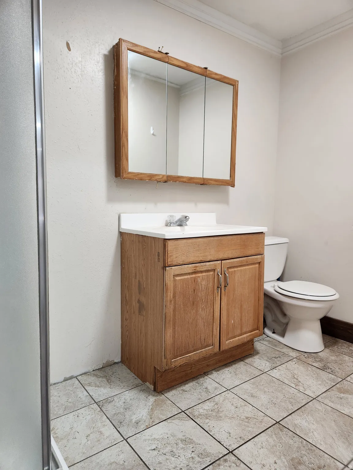 Vanity with wood-finish cabinetry, white countertop, and integrated sink