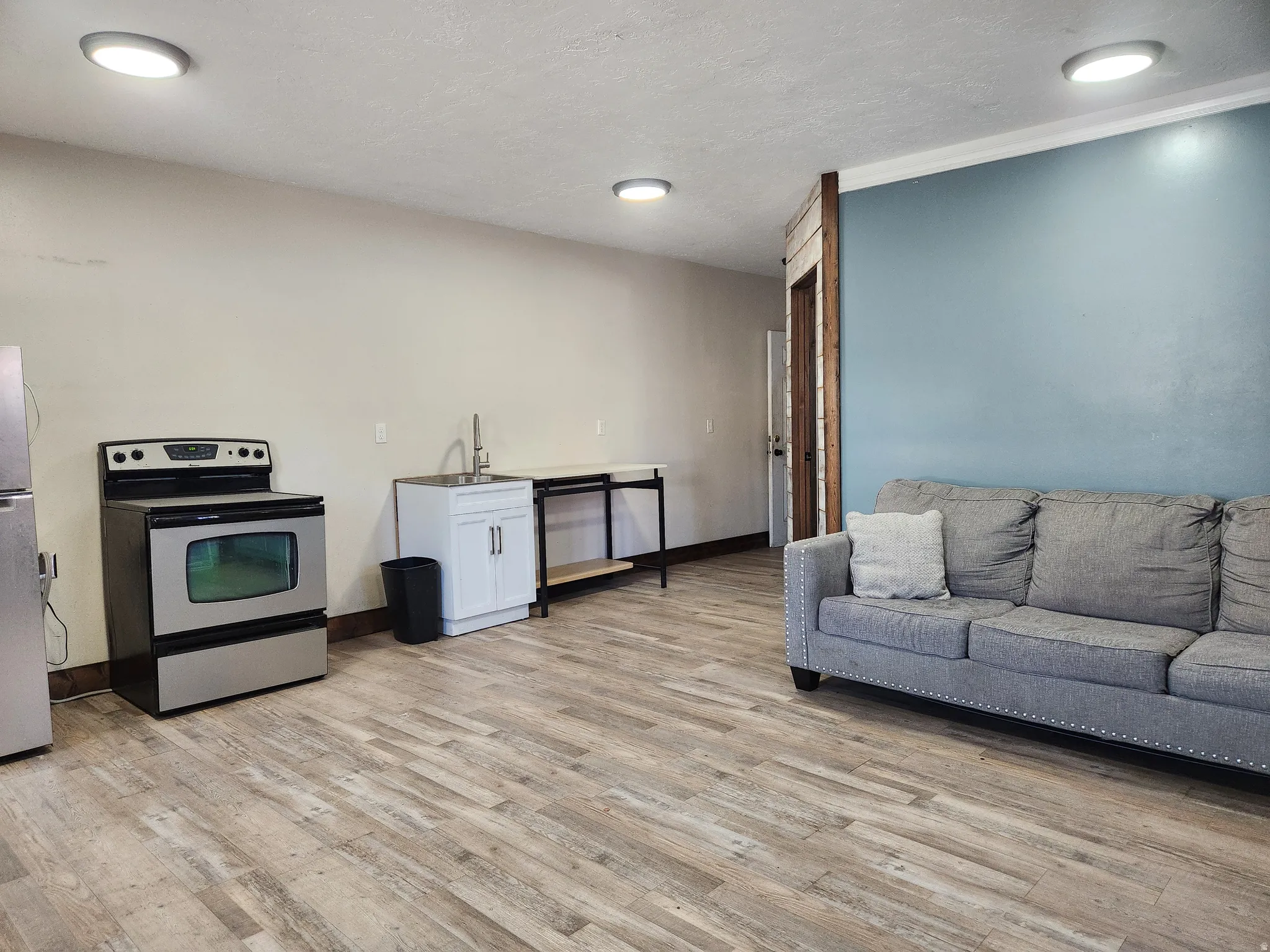 Stainless steel range, wood-finish flooring, white cabinetry with a single-basin sink, and recessed ceiling lighting