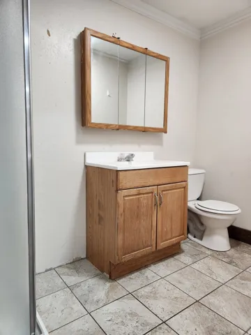Vanity with wood-finish cabinetry, white countertop, and integrated sink