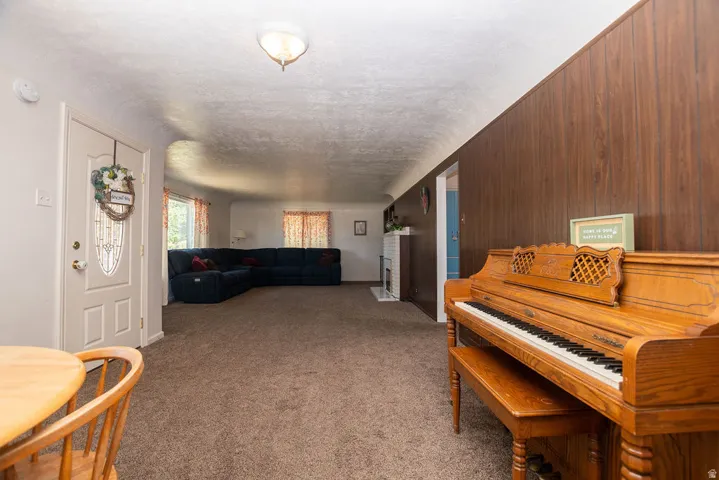Neutral color palette, wood-finish wall paneling, white interior door with decorative glass inlay, recessed ceiling light fixture, and carpeted flooring