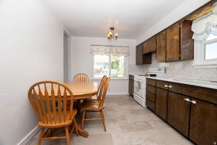 Functional kitchen featuring wood-finish cabinetry, white countertops, tile flooring, and a white electric range