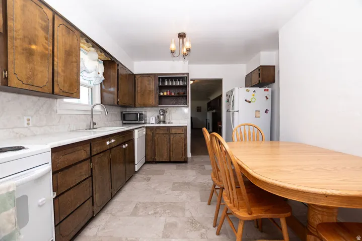 Kitchen featuring dark wood-finish cabinetry, white countertops, and a white sink with a gooseneck faucet