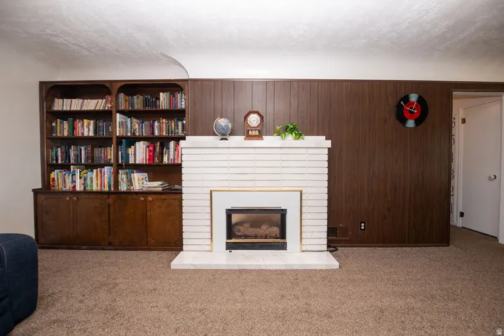 White brick fireplace with an integrated firebox, wood-paneled wall, and a built-in wood cabinet with shelving
