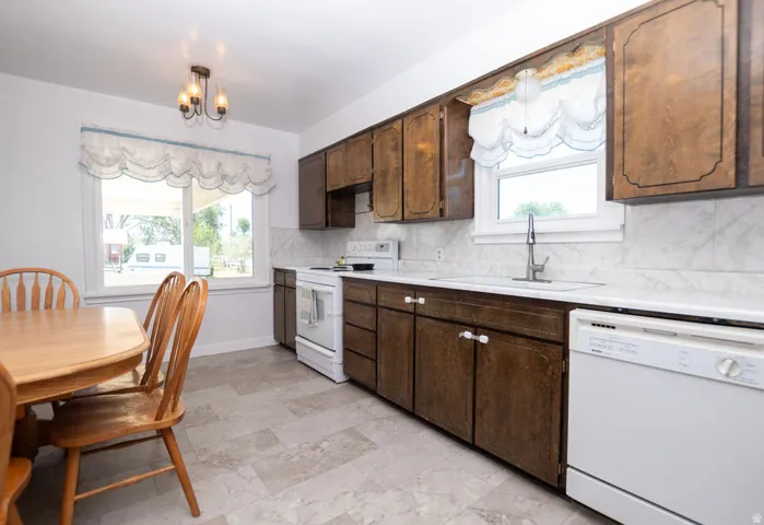 Kitchen featuring wood-finish cabinetry, white countertops, a tile backsplash, and a built-in dishwasher