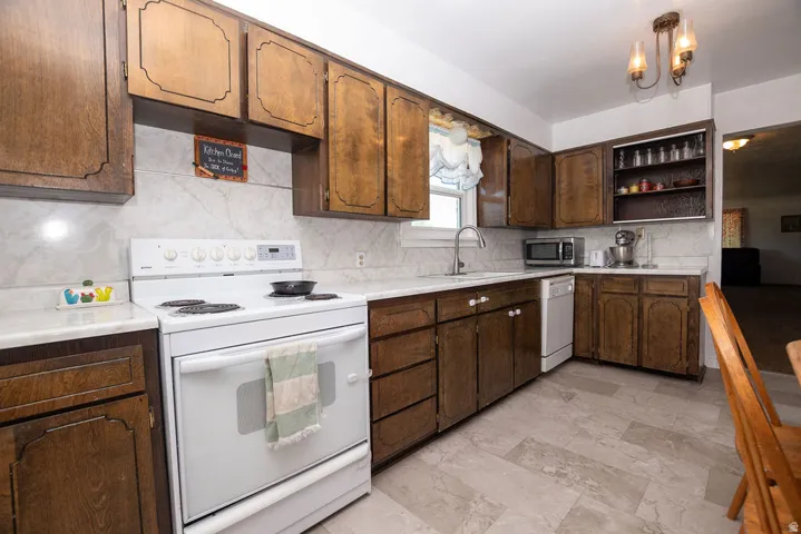 Kitchen featuring wood cabinetry, white countertops, a white electric range, and a built-in dishwasher