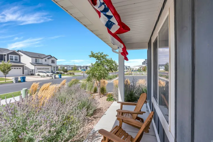 Covered front porch with white columns, concrete flooring, and blue siding