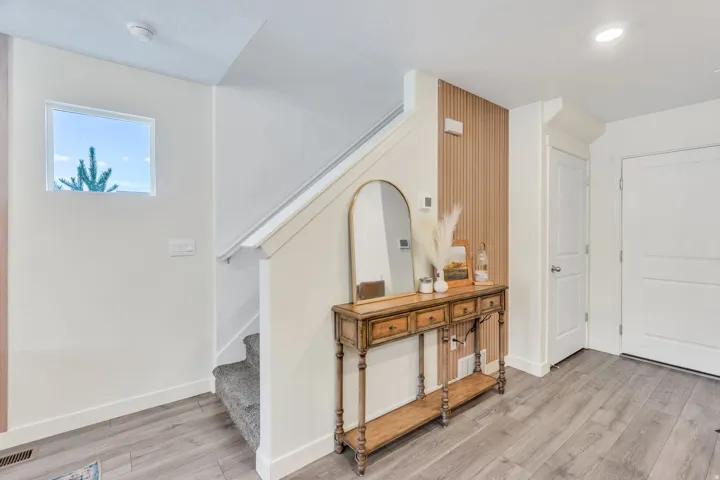 Wood-finish flooring, white walls, white doors, and a staircase with carpeted treads
