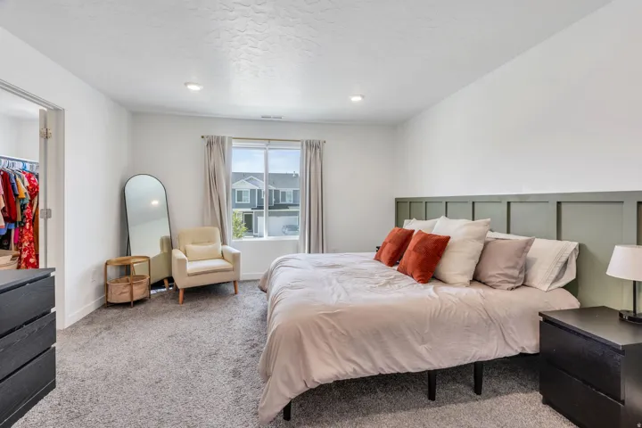 Spacious bedroom featuring light gray carpeting and a paneled accent wall